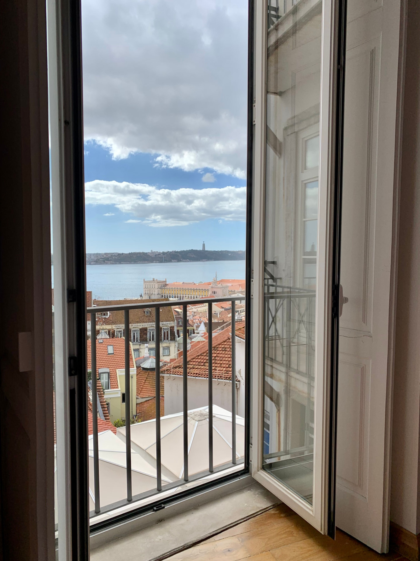 Open door with sunlight streaming into a Porto apartment, framing the city rooftops and the river beyond
